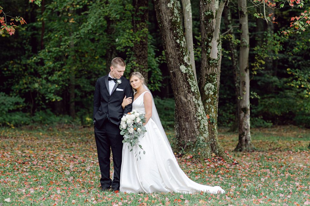 a newlywed couple linking arms under a tree